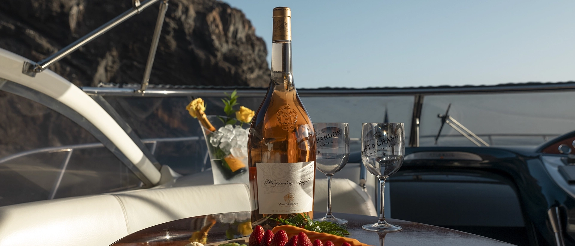 Botella de rosado y copas en la mesa de cubierta